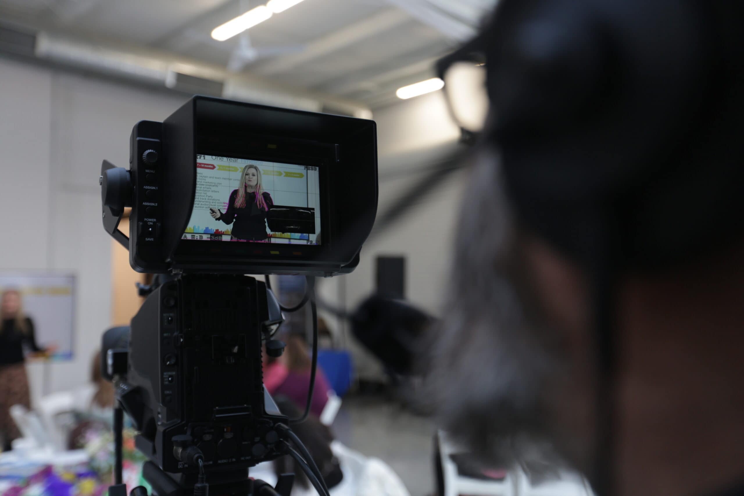 Woman stands in front of camera, being recorded, for a live stream.